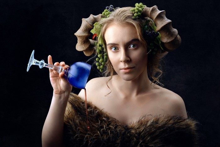 Woman with horns and grapes holding a wine glass
