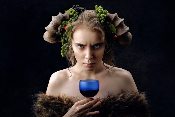 Woman with horns and grapes holding a glass of wine