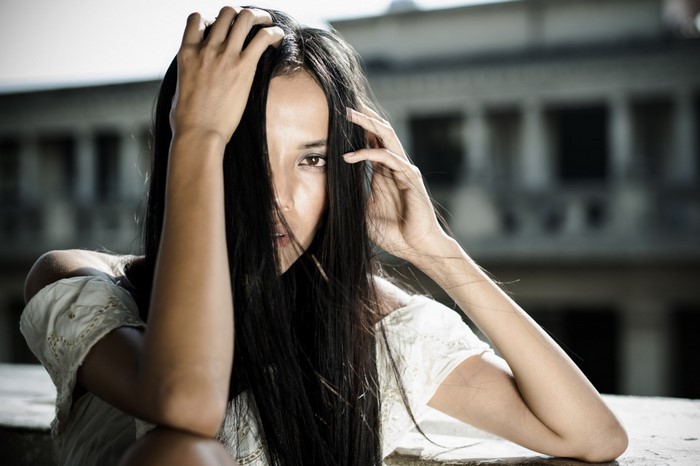 Woman with long black hair touching her head