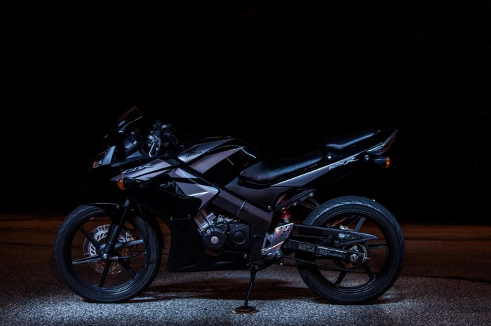 Black Honda CBR125R motorcycle on dark background