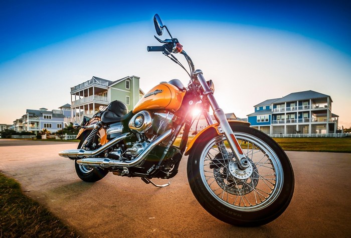 Orange Harley Davidson motorcycle parked by beach houses