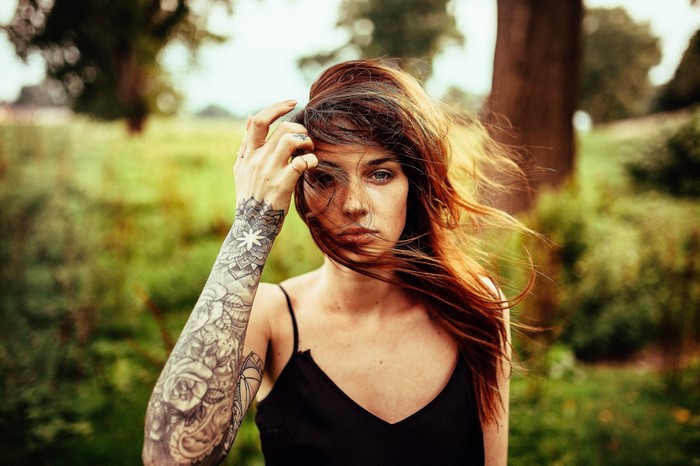 Woman with tattoos and windblown hair in a forest