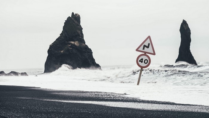 Black sand beach with rock formations and warning signs
