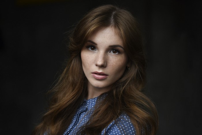 Woman with freckles and brown hair in a blue polka dot shirt