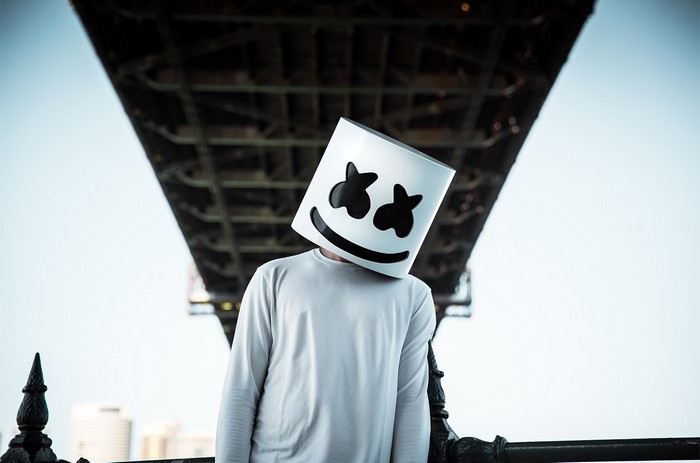 Marshmello wearing a white shirt under a bridge