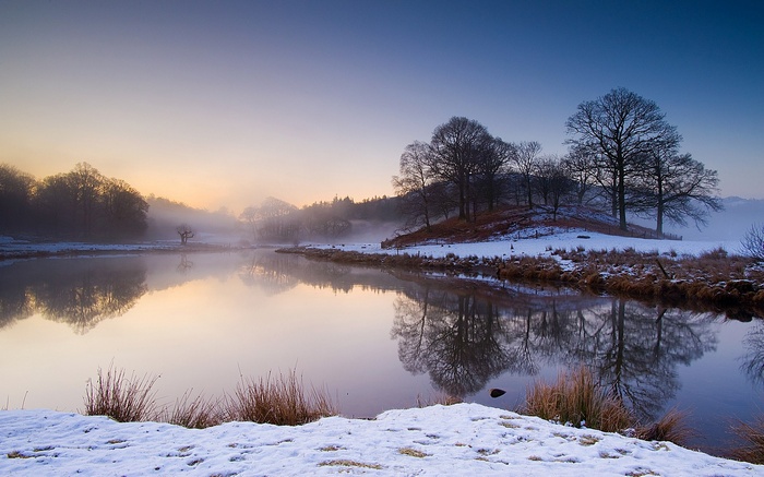 Winter lake at sunrise with mist and reflections