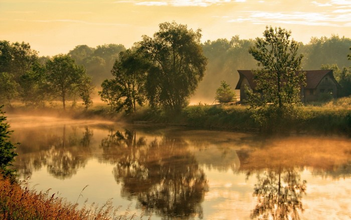Misty river at sunrise with a house in the background