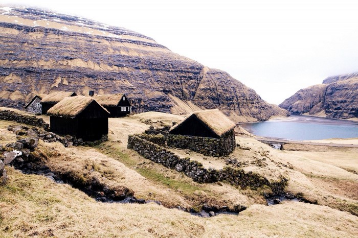 Traditional turf-roofed houses by a lake in a mountainous landscape
