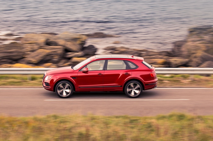 Red Bentley Bentayga V8 driving on coastal road