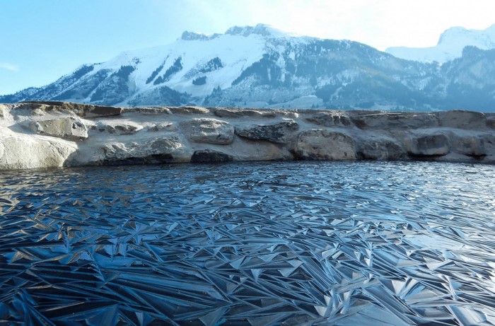 Frozen lake with ice patterns and snowy mountains
