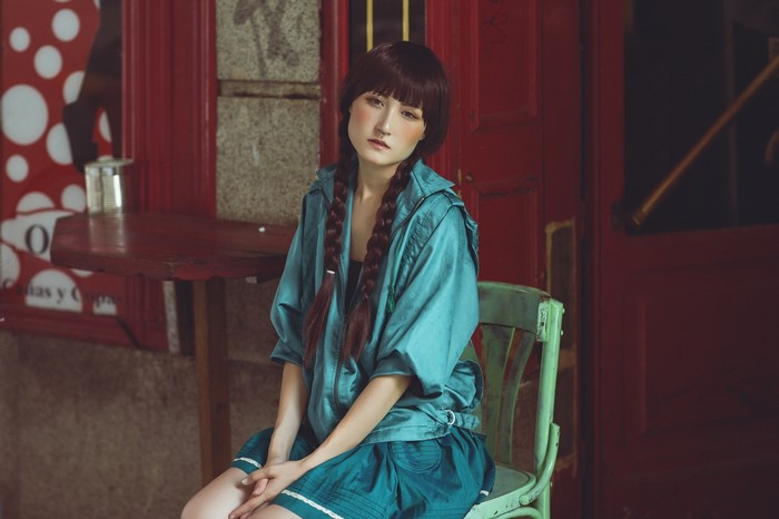 Asian woman with braided hair sitting on a chair