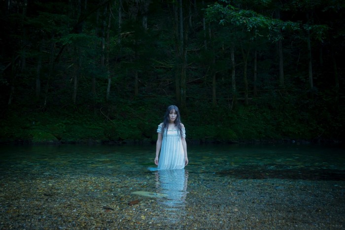 Woman in white dress standing in a forest stream