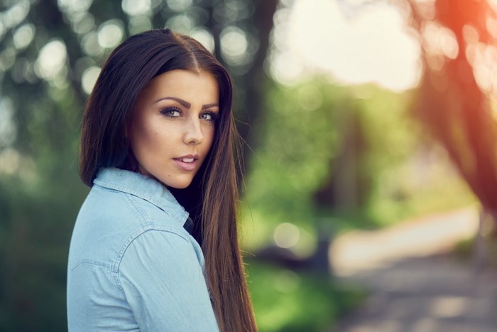 Woman with long brown hair wearing a denim shirt
