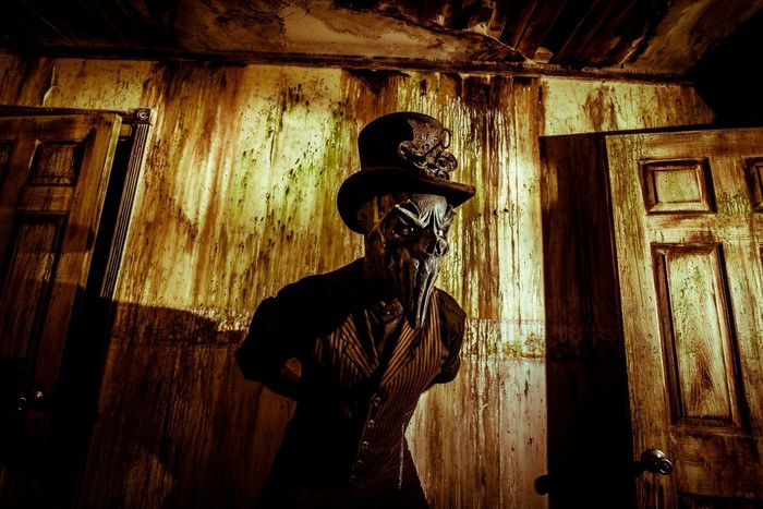 Man in plague doctor mask and top hat in a derelict room