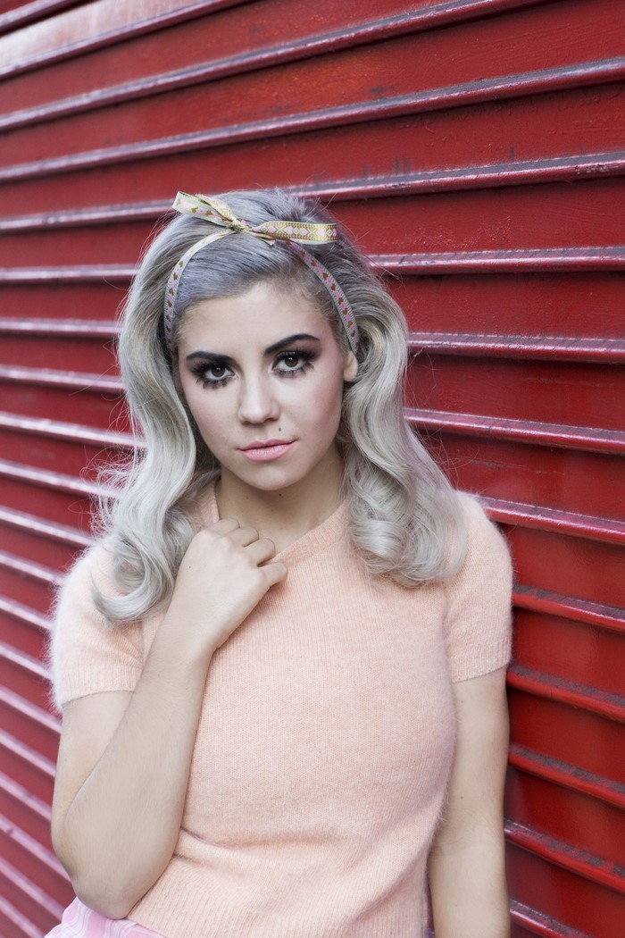 Marina Diamandis with blonde hair and pink sweater