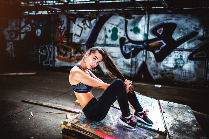 Woman in gym clothes sitting in front of graffiti