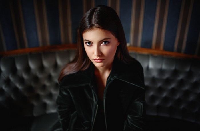 Woman with black hair sitting on a leather couch
