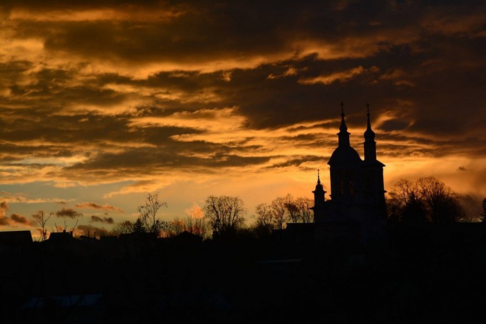 Silhouette of church towers against a dramatic sunset sky