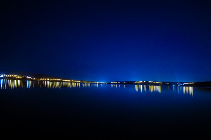 City lights reflecting on a calm lake at night