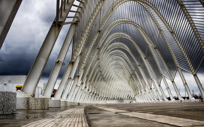 Modern architectural structure with arched roof and cloudy sky