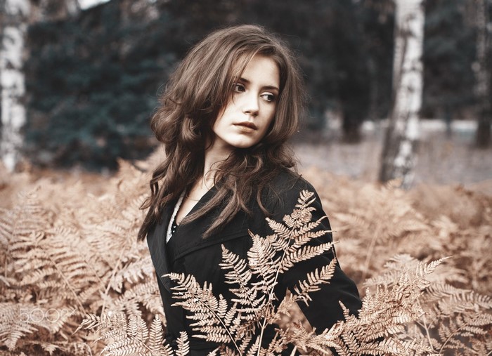 Woman with long wavy brown hair in a black coat