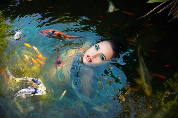 Woman swimming with koi fish in a pond