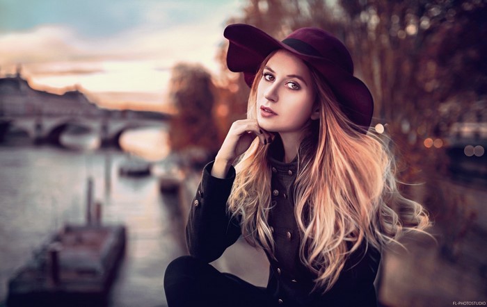 Woman wearing a hat and coat by a river