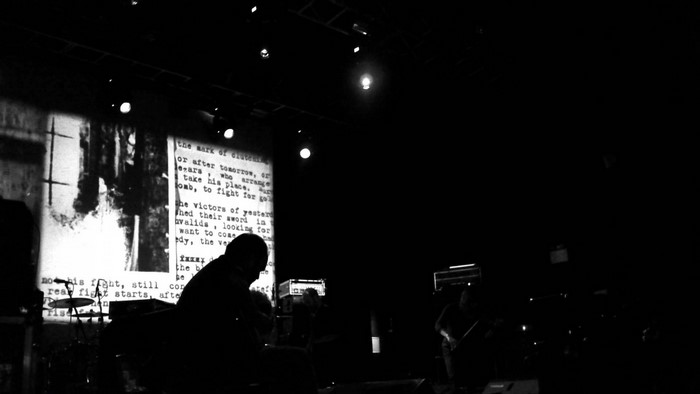Concert performance with projected text and silhouettes