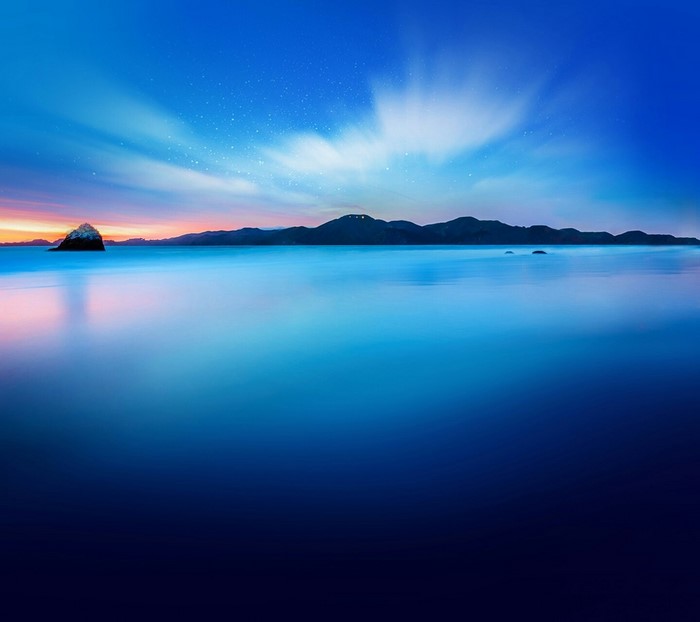 Ocean horizon with island and sky at sunset