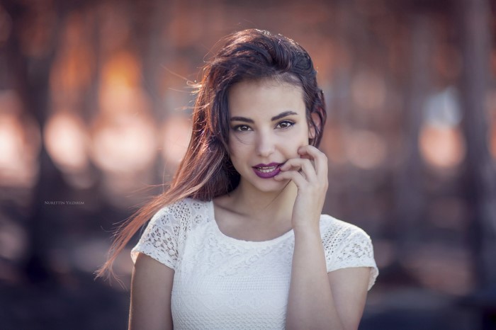 Woman with long brown hair wearing a white lace top