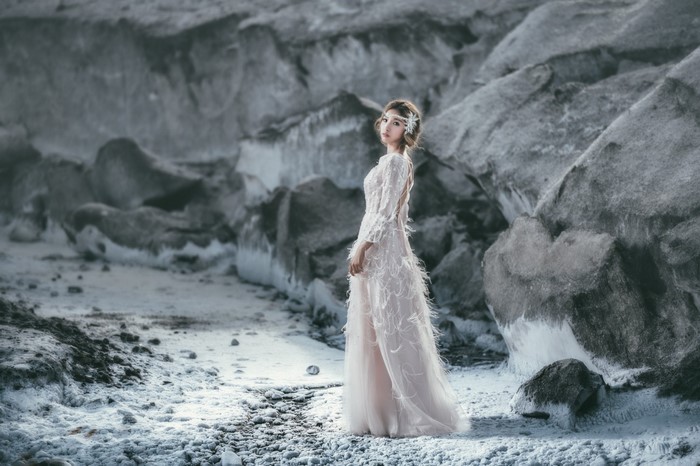 Woman in a white dress in a rocky, icy landscape