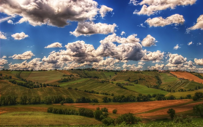 Rolling hills with cultivated fields under a cloudy sky