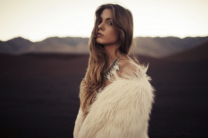 Woman with long brown hair wearing a fur coat and necklace