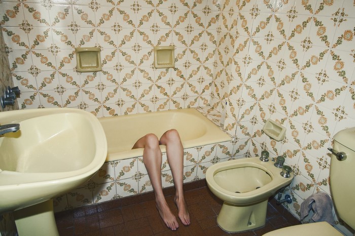Legs in a bathtub in a tiled bathroom