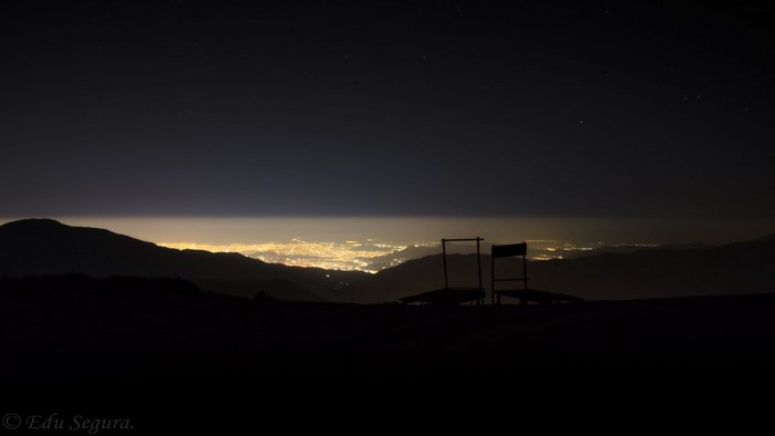 City lights at night seen from mountains with chairs