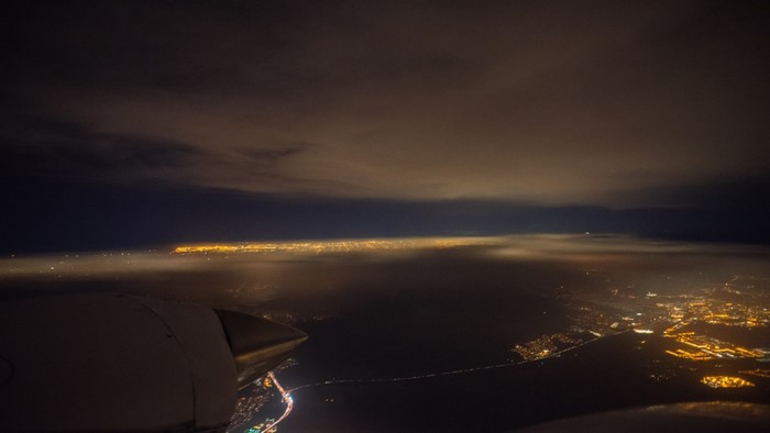 Airplane view of city lights at night over clouds