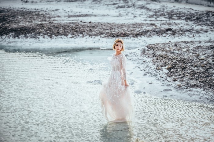 Woman in a white dress standing in shallow water
