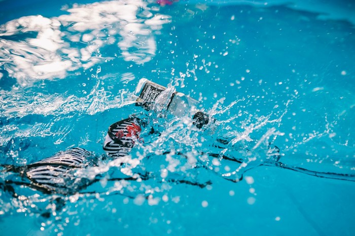 Bottle and swimwear splashing in blue water