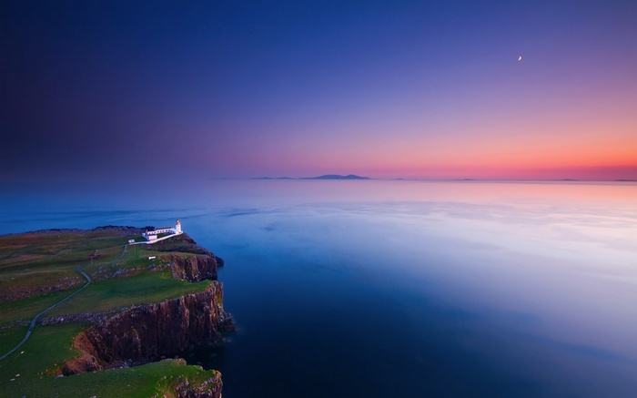 Lighthouse on a cliff overlooking the sea at sunset