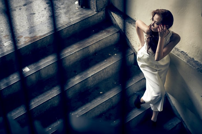 Woman in white jumpsuit on dark stairs