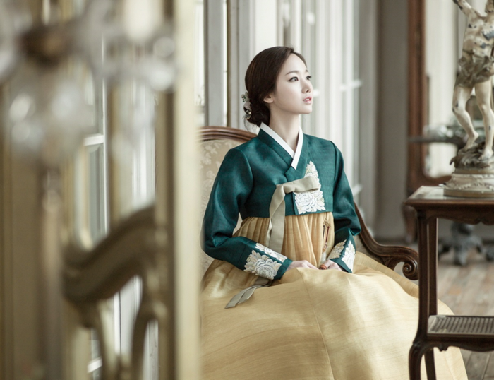 Woman in traditional Korean Hanbok dress sitting in a chair