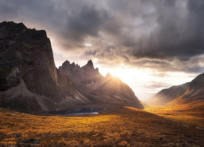 Sunlight streams through a mountain valley with a lake