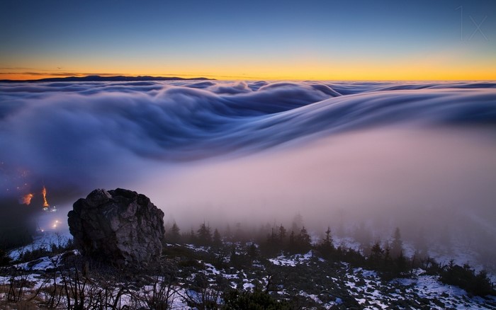 Waves of fog over mountains at sunrise