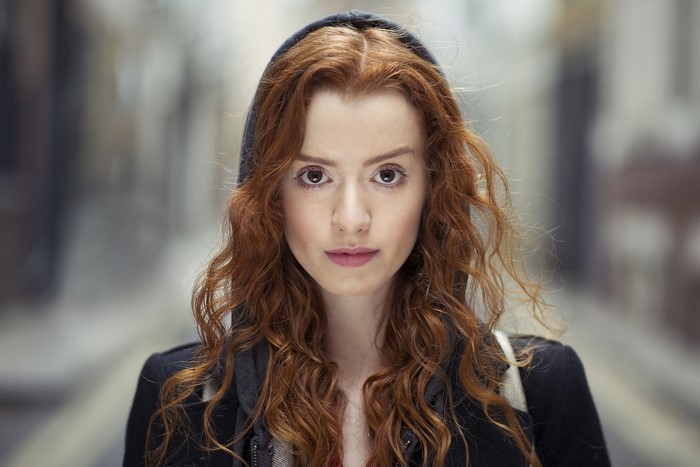 Woman with long wavy red hair wearing a hood