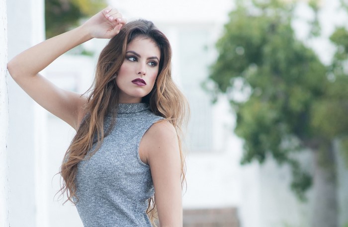 Woman with long brown hair wearing a grey dress