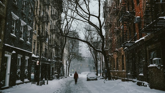 Person walking down a snowy city street in winter
