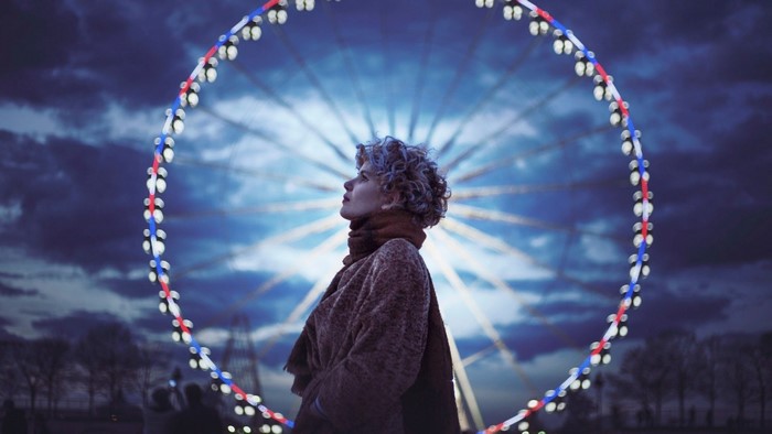 Woman looking up at a Ferris wheel at night