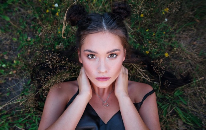 Woman with space buns lying in grass