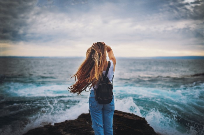 Woman with long hair on a rocky shore with ocean waves