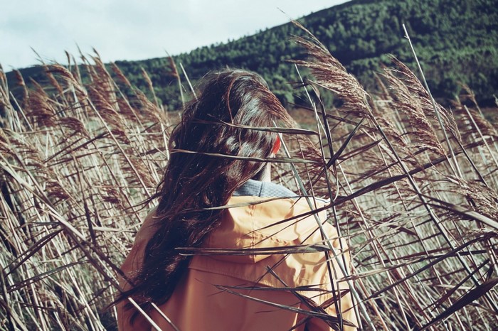 Woman in orange jacket in a field of tall grass